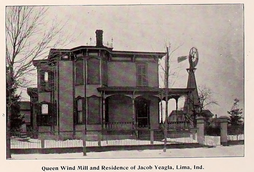 A photograph printed in an 1893 county atlas. A two storey house with a bay window, a deep porch and a brick chimney stands behind a picket fence, with bare trees at either side. To the right of the house a wooden tower rises to a bladed wheel and a tail vane. A printed line beneath the photograph reads Queen Wind Mill and Residence of Jacob Yeagla, Lima, Ind.